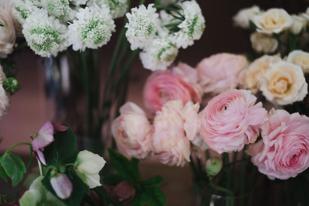 Bouquets of white, pink, and green flowers in vases on a dark background by The Dreamt Garden Madison AL florist.