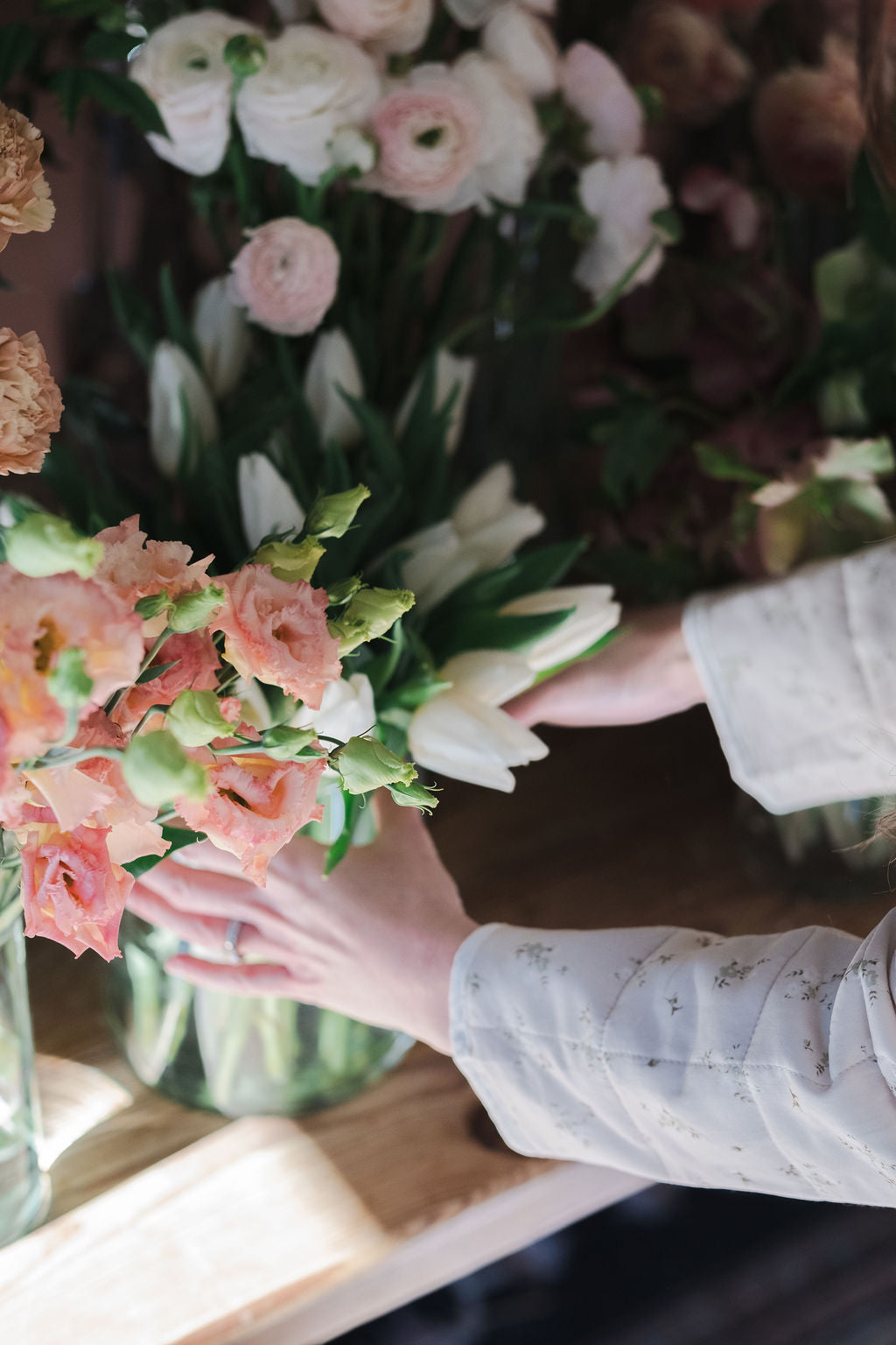 The Dreamt Garden florist in Madison AL arranging flowers with a focus on hands and floral arrangement of tulips ranunculus and spring flowers.