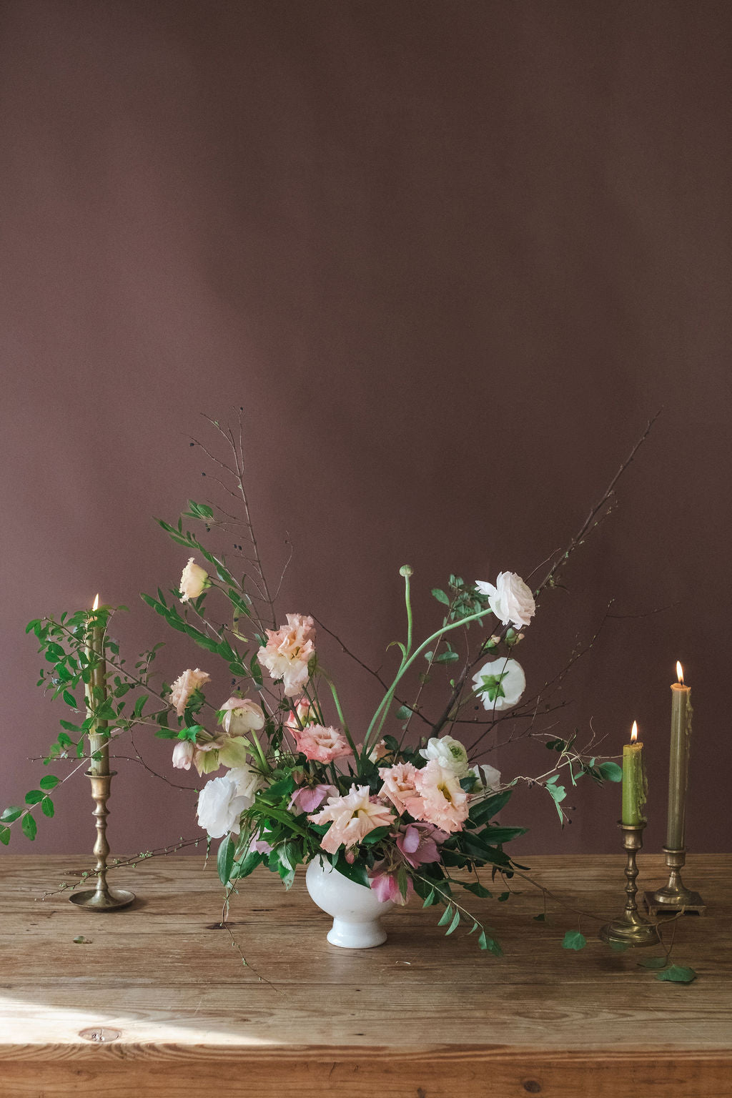 Floral arrangement with garden cottage flowers in a white vase on a wooden table with candles against a brown background. Used for Corporate Events, Bridal Showers, Baby Showers, and Sympathy Flowers.