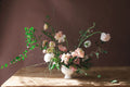 Large garden style floral arrangement in a white vase on a wooden table with premium flowers including ranunculus, lisianthus, spirea and hellebores. Perfect for small and intimate weddings in North Alabama.