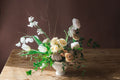 Floral arrangement with Roses carnations sweet peas vines and nandina in a white vase on a wooden table.  Cottage and garden inspired flowers from The Dreamt Garden.