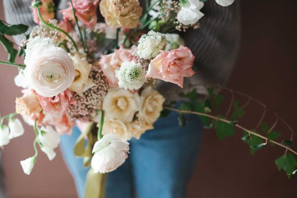 Garden style bouquet with roses, ranunculus, sweet peas, scabiosa, lisianthus, ivy and more.  Bouquet is held by The Dreamt Garden florist in Madison AL, flower delivery to Huntsville, Alabama.