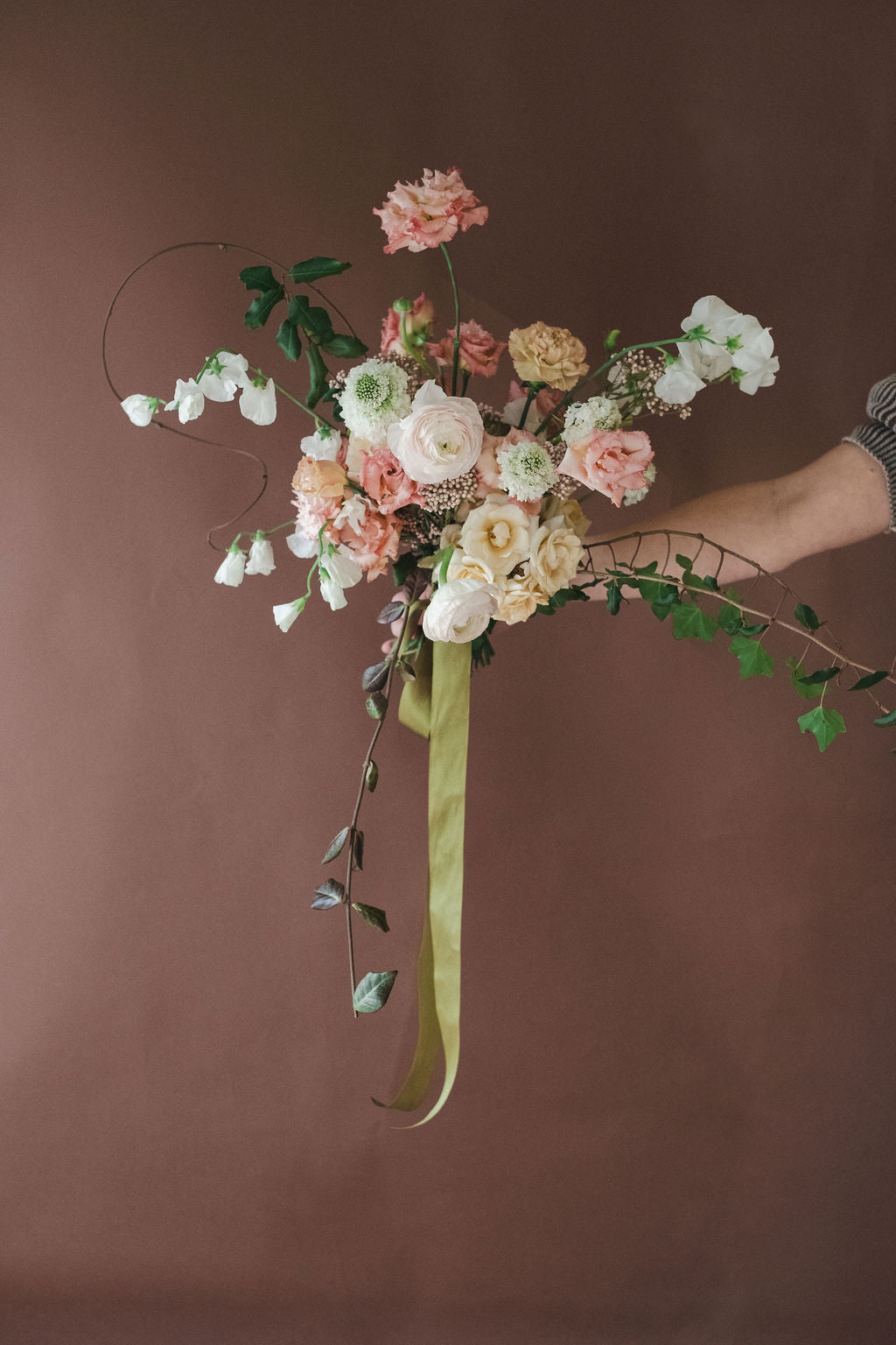 Garden style floral arrangement with a green ribbon against a brown background by The Dreamt Garden, wedding florist in Madison AL.